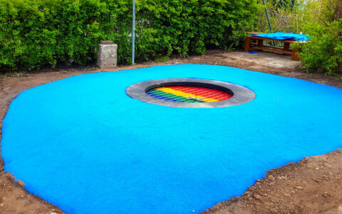 Eine blaue Teppichvlies-Fläche als Fallschutz um einem Trampolin.